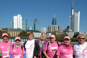 Gruppe von älteren Frauen in pinken Shirts stehen nach dem Brustkrebslauf vor der Skyline von Mainhatten in Frankfurt